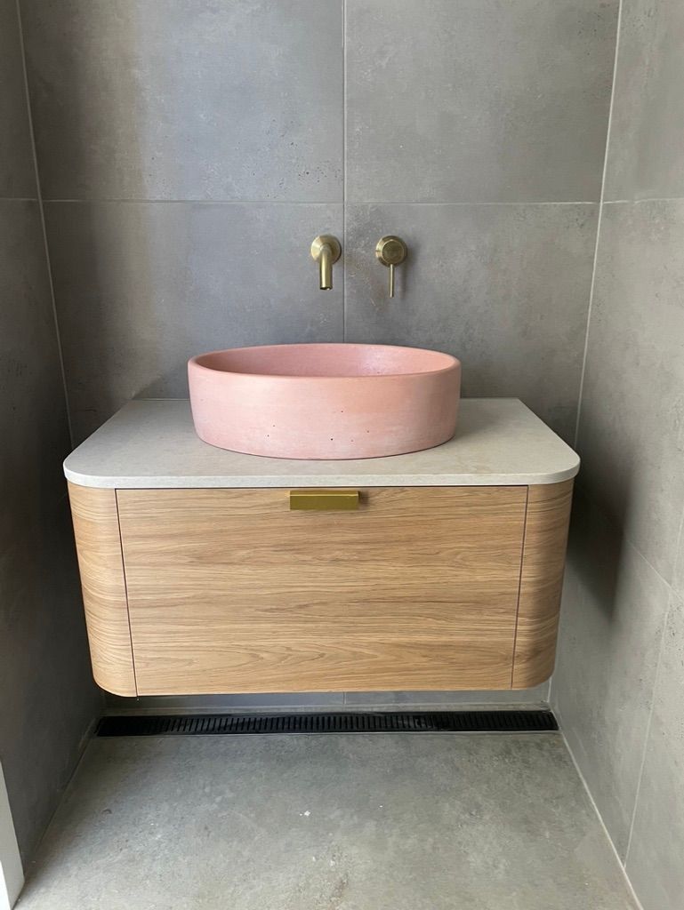 Floating wooden vanity with pink basin and gold fixtures in a modern bathroom. — All Stars Plumbing In Dapto, NSW