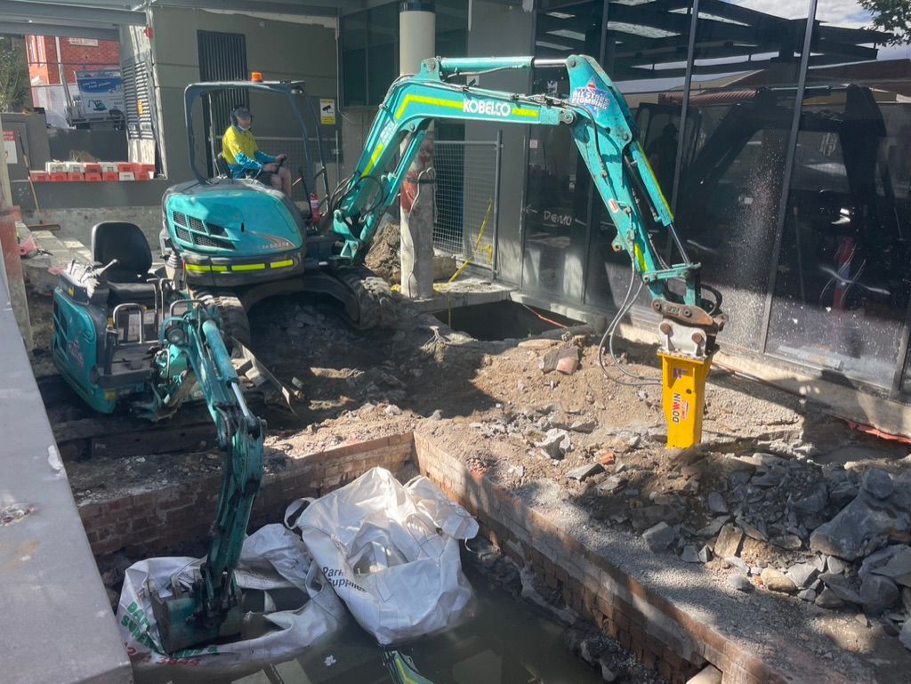 Excavator at construction site digs in dirt with yellow jackhammer. — All Stars Plumbing In Dapto, NSW