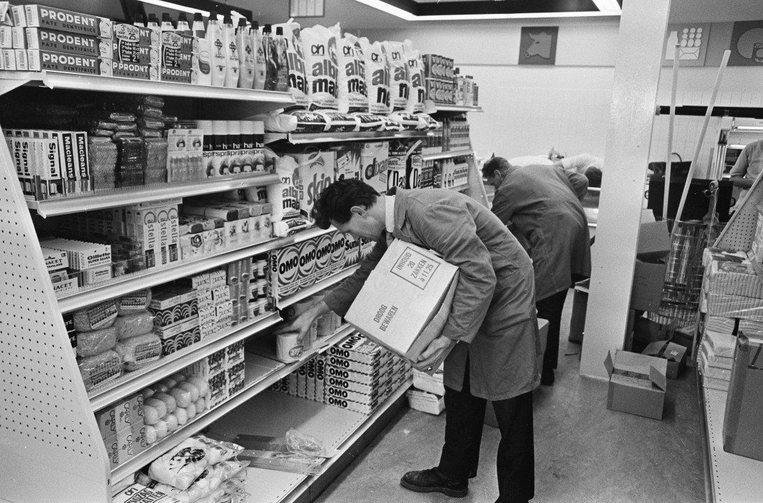 Een zwart-witfoto van twee mannen die naar de planken in een supermarkt kijken.