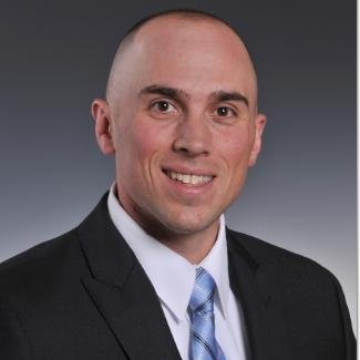 A woman wearing a black shirt and a watch is standing in front of a black background.