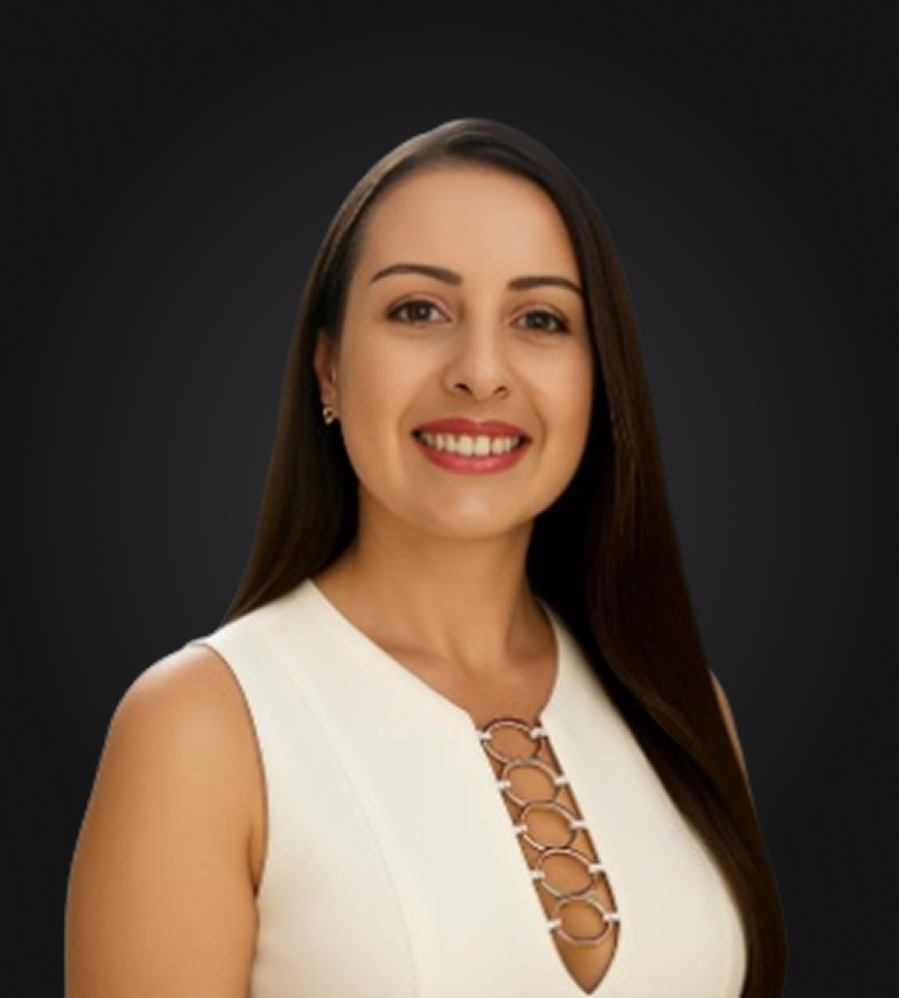 A woman wearing a black shirt and a watch is standing in front of a black background.