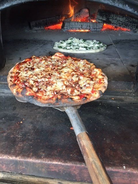 A pizza is being taken out of an oven on a spatula