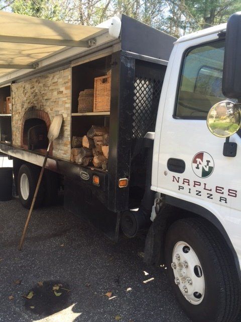 A naples pizza truck is parked in a parking lot