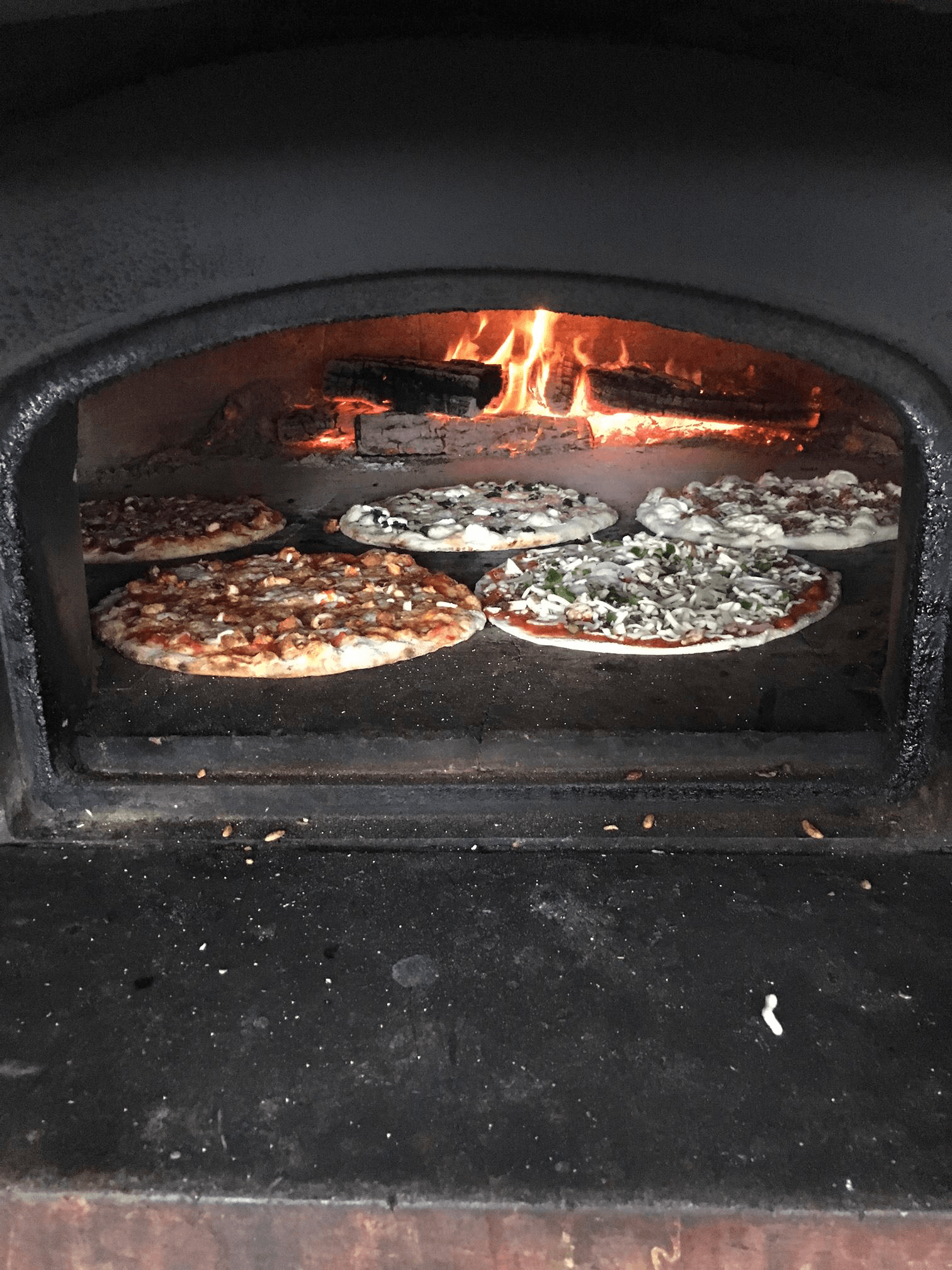 Four pizzas are cooking in a wood fired oven