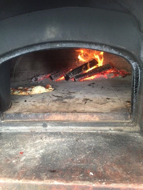 A pizza is being cooked in a wood fired oven.