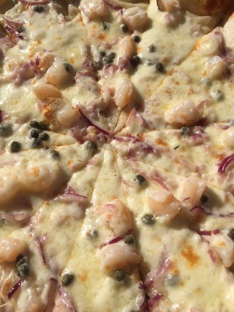 A close up of a pizza with shrimp and onions
