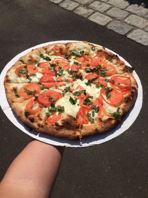 A person is holding a pizza on a paper plate