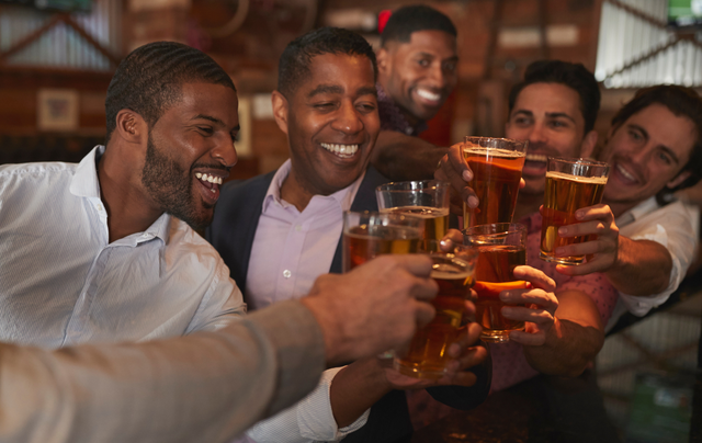 A group of men are toasting with beer in a bar.