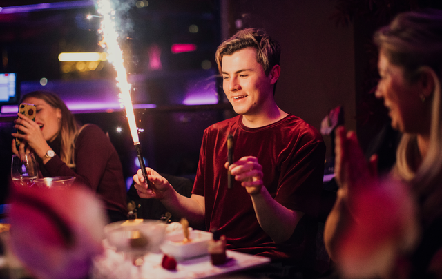 A man is sitting at a table with a sparkler in his hand.