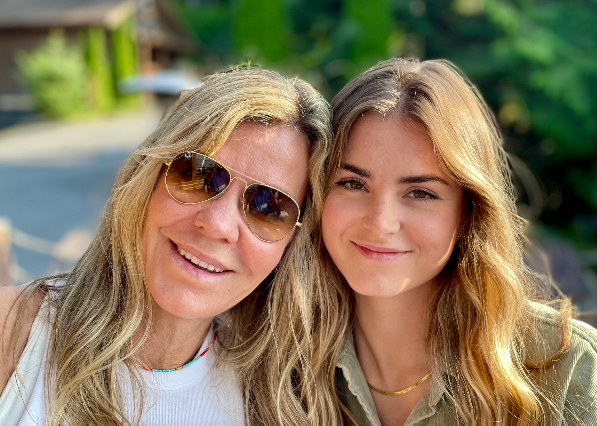Two women wearing sunglasses are posing for a picture together.