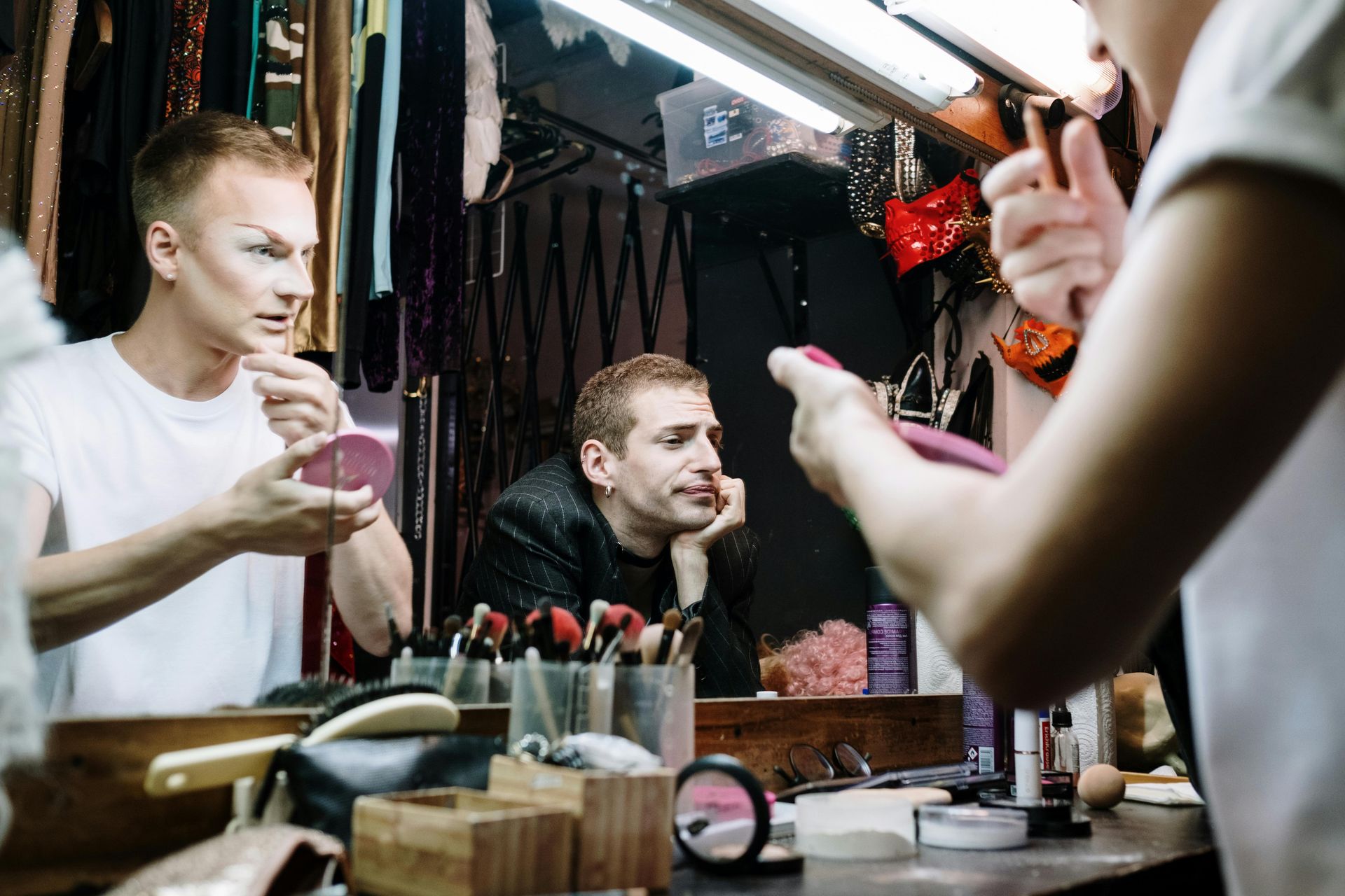 A woman is applying makeup to a man in front of a mirror.