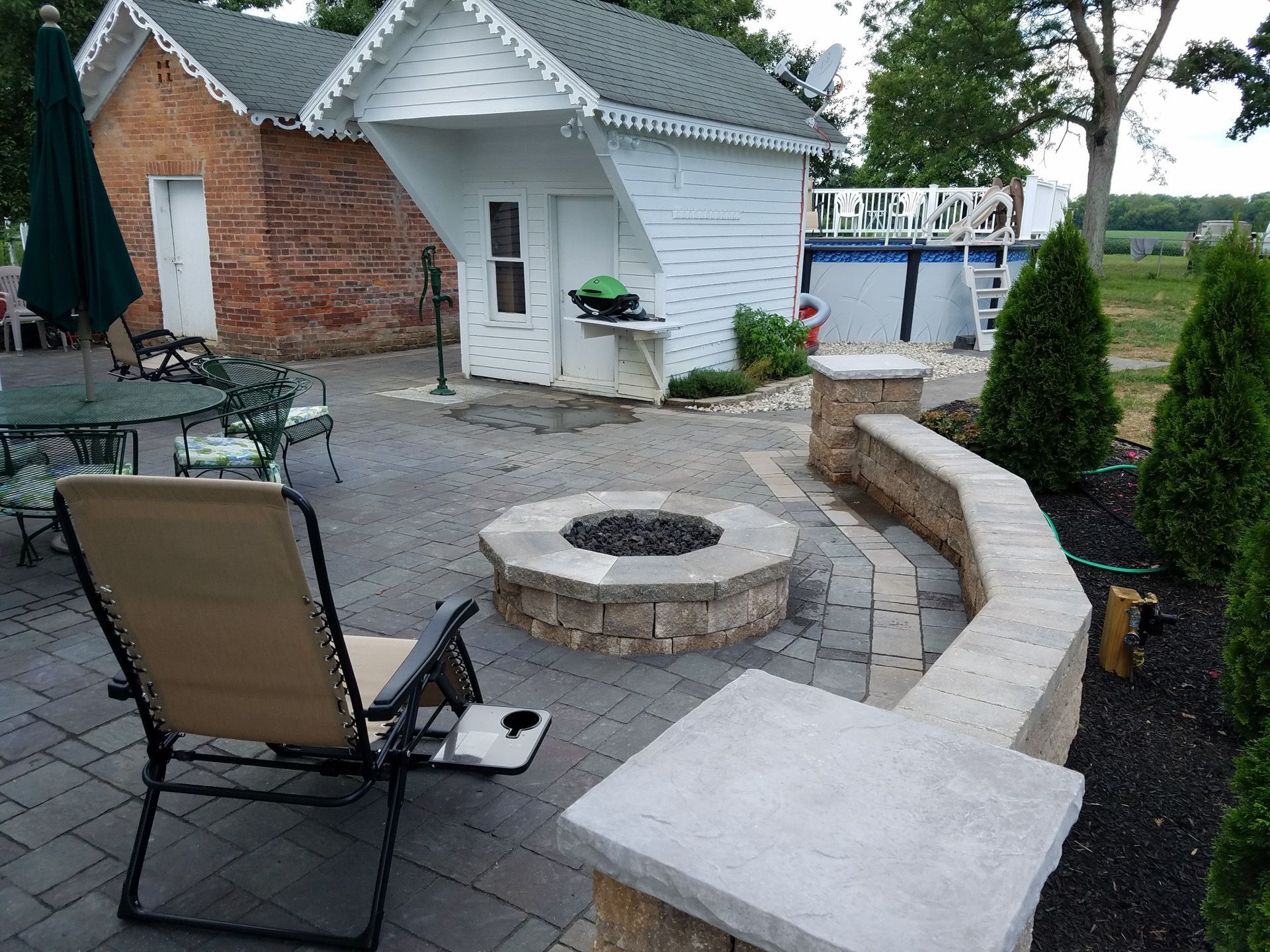 A patio with a fire pit and chairs in front of a house
