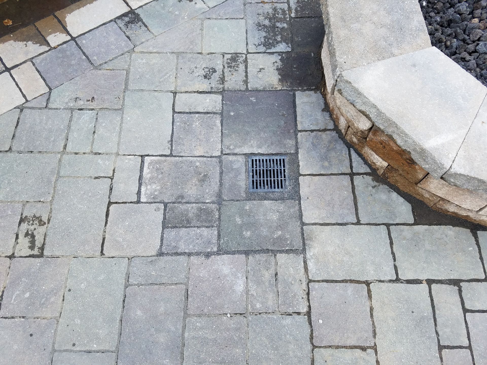 A drain hole in the middle of a brick walkway