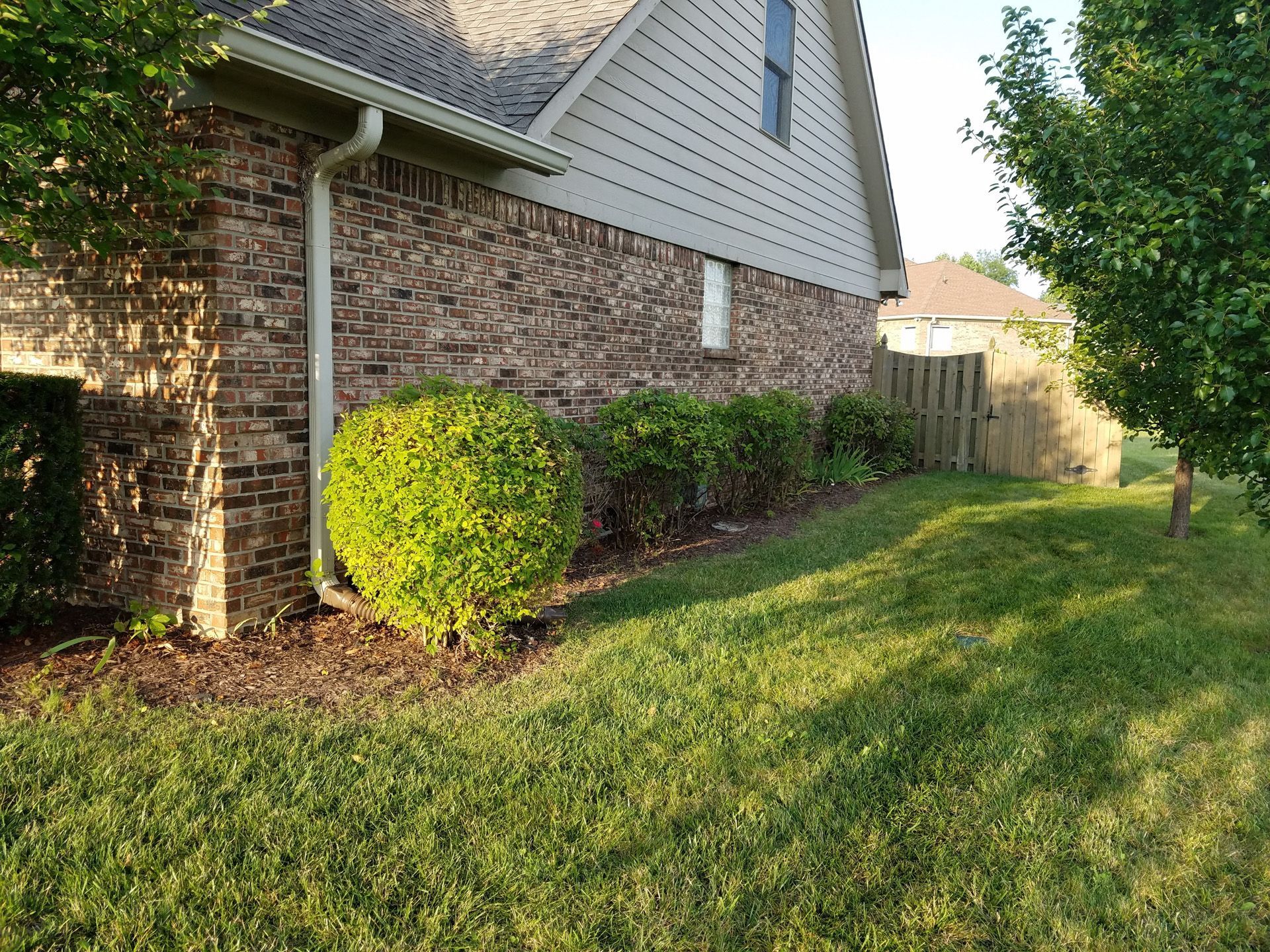 A brick house with a lush green lawn in front of it.