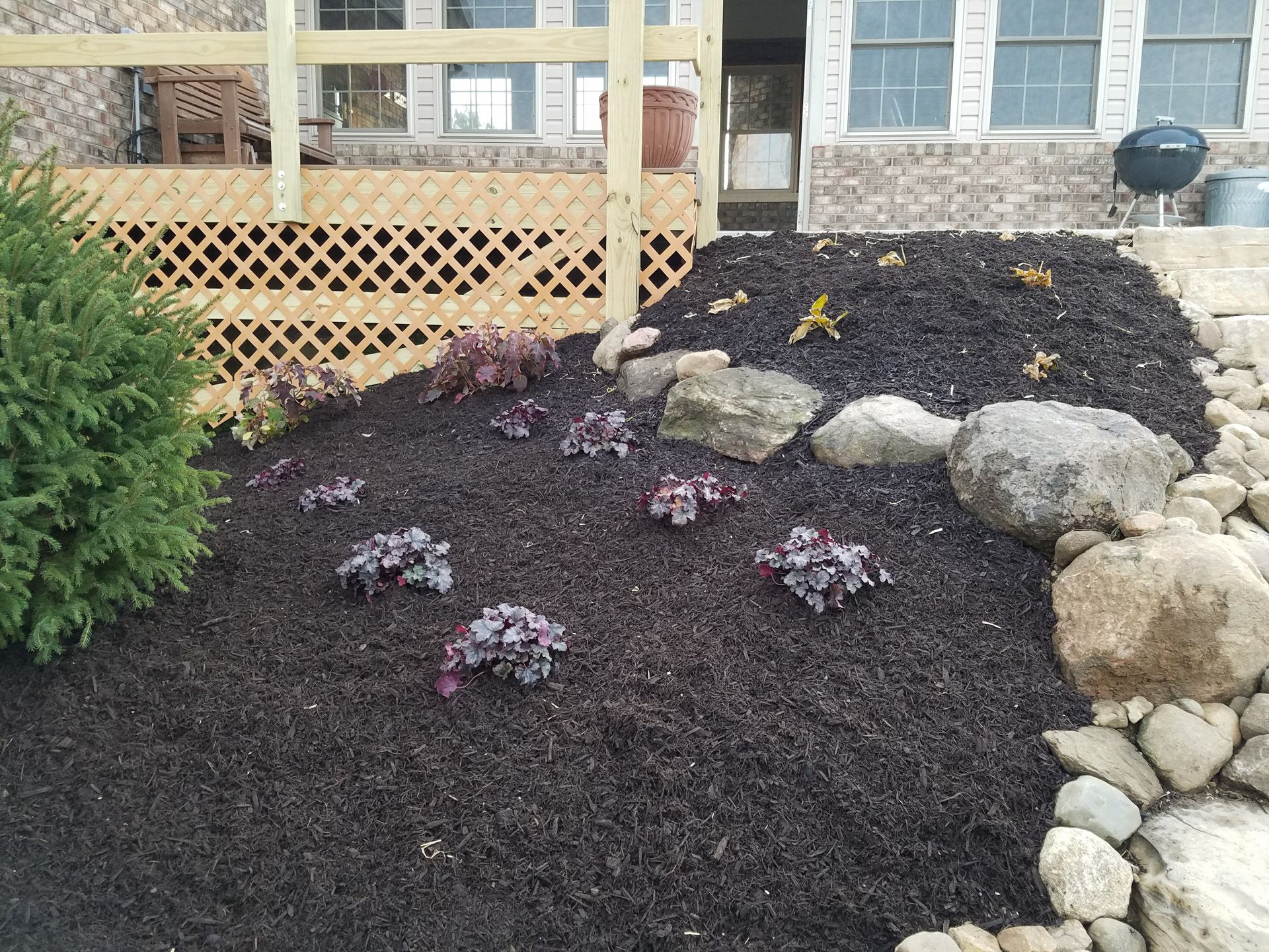 A garden with rocks and flowers in front of a house.