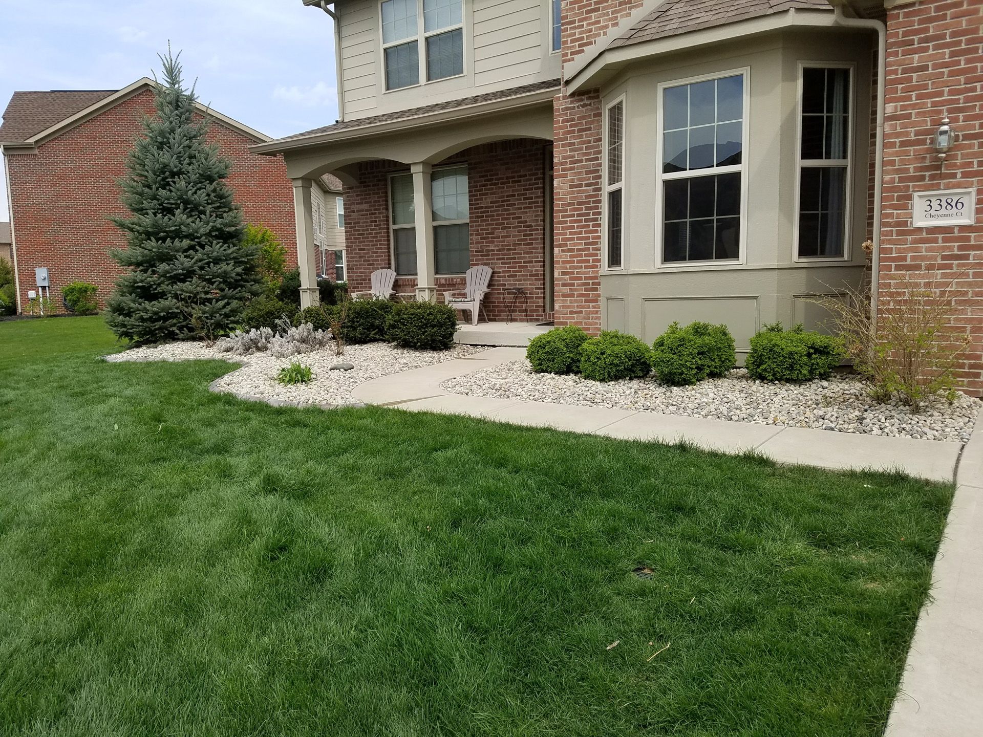 A brick house with a large lawn in front of it.