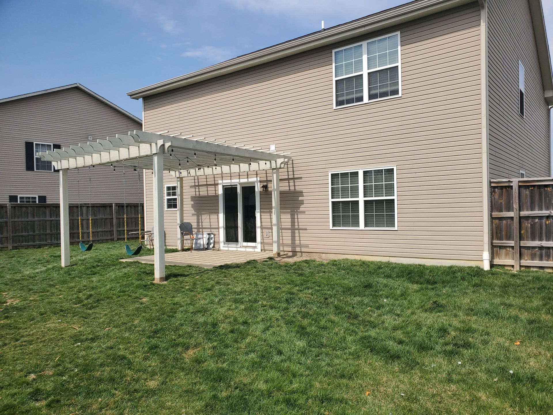 The backyard of a house with a pergola and a patio.