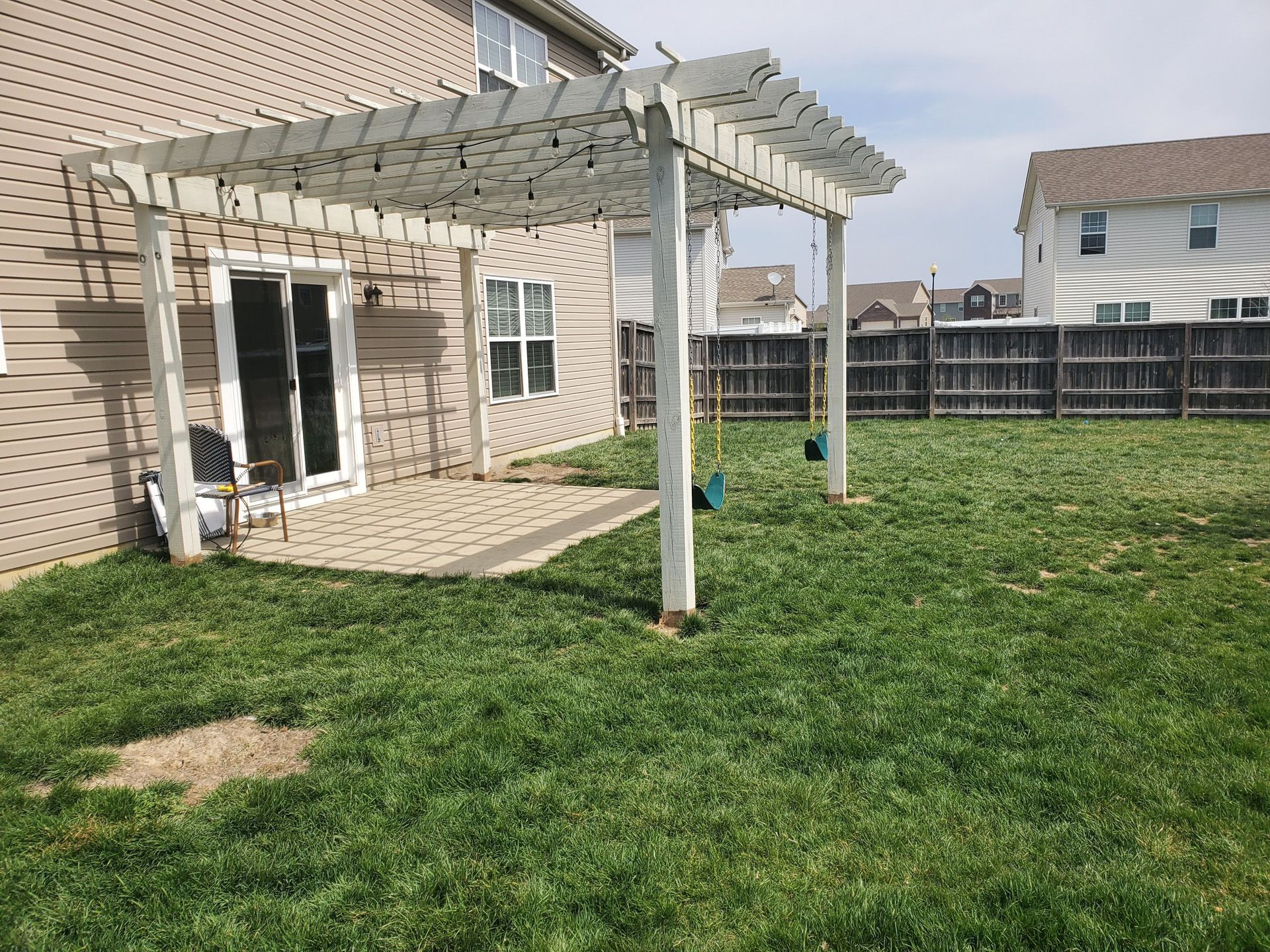 There is a pergola in the backyard of a house.