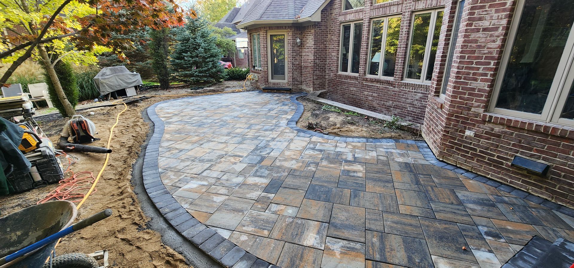 A brick house with a patio being built in front of it.