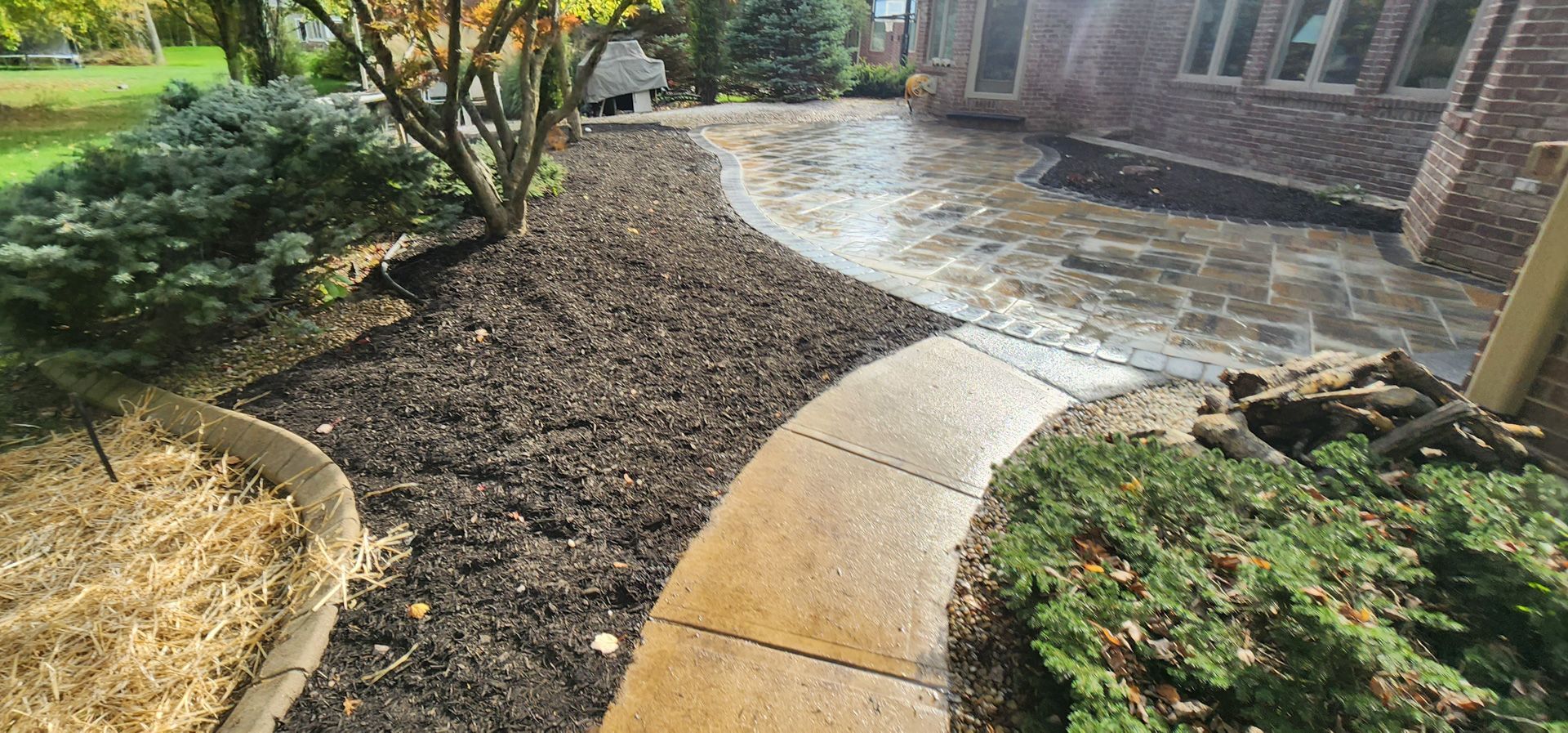 A walkway leading to a brick house with a patio in the background.