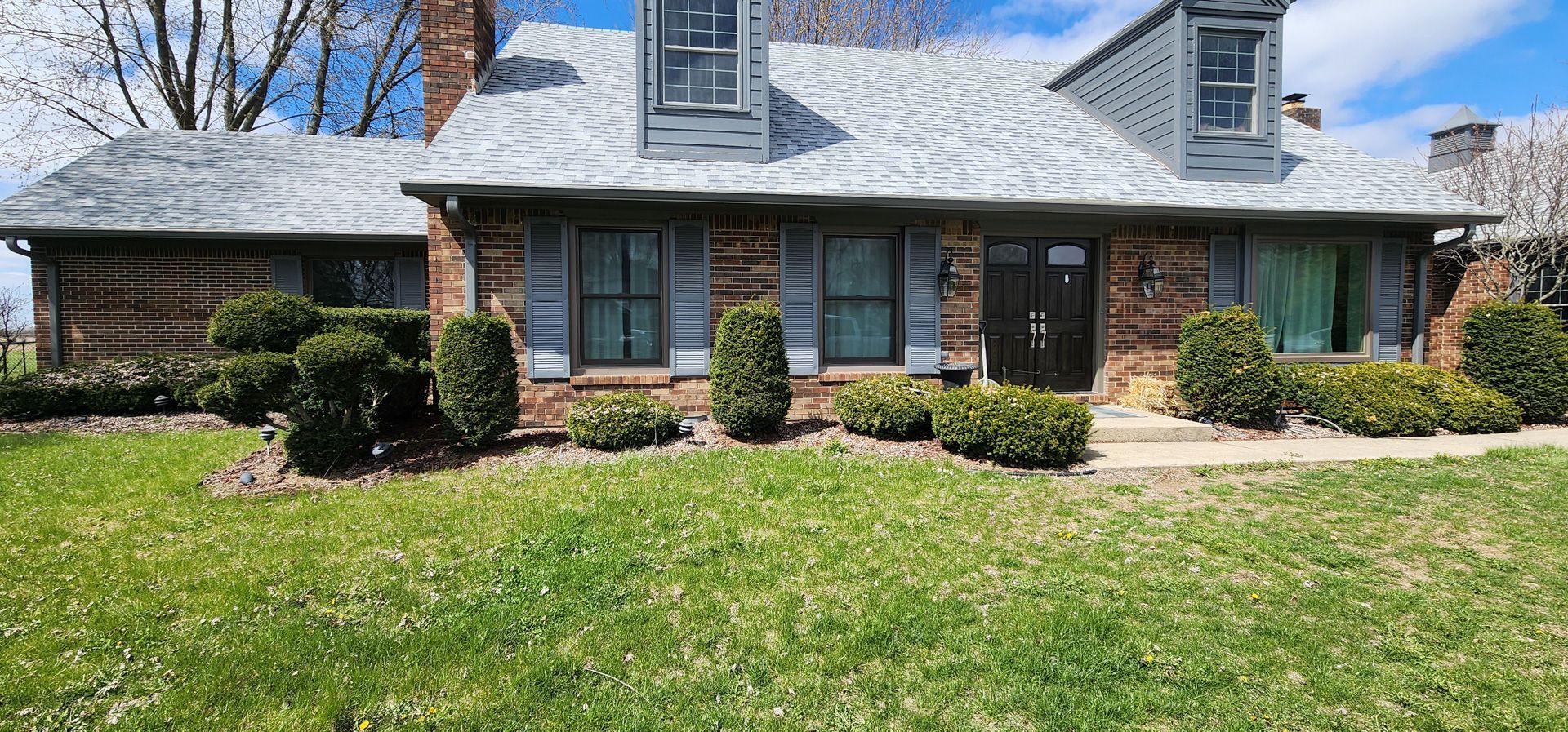 A large brick house with a lush green lawn in front of it.