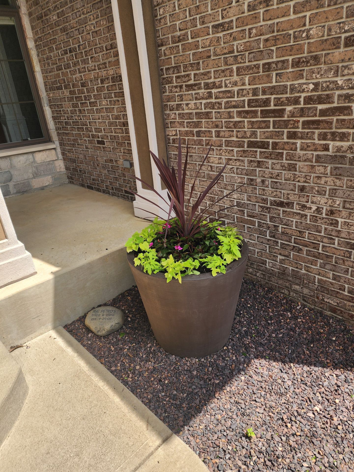 A large pot filled with flowers is sitting in front of a brick building.