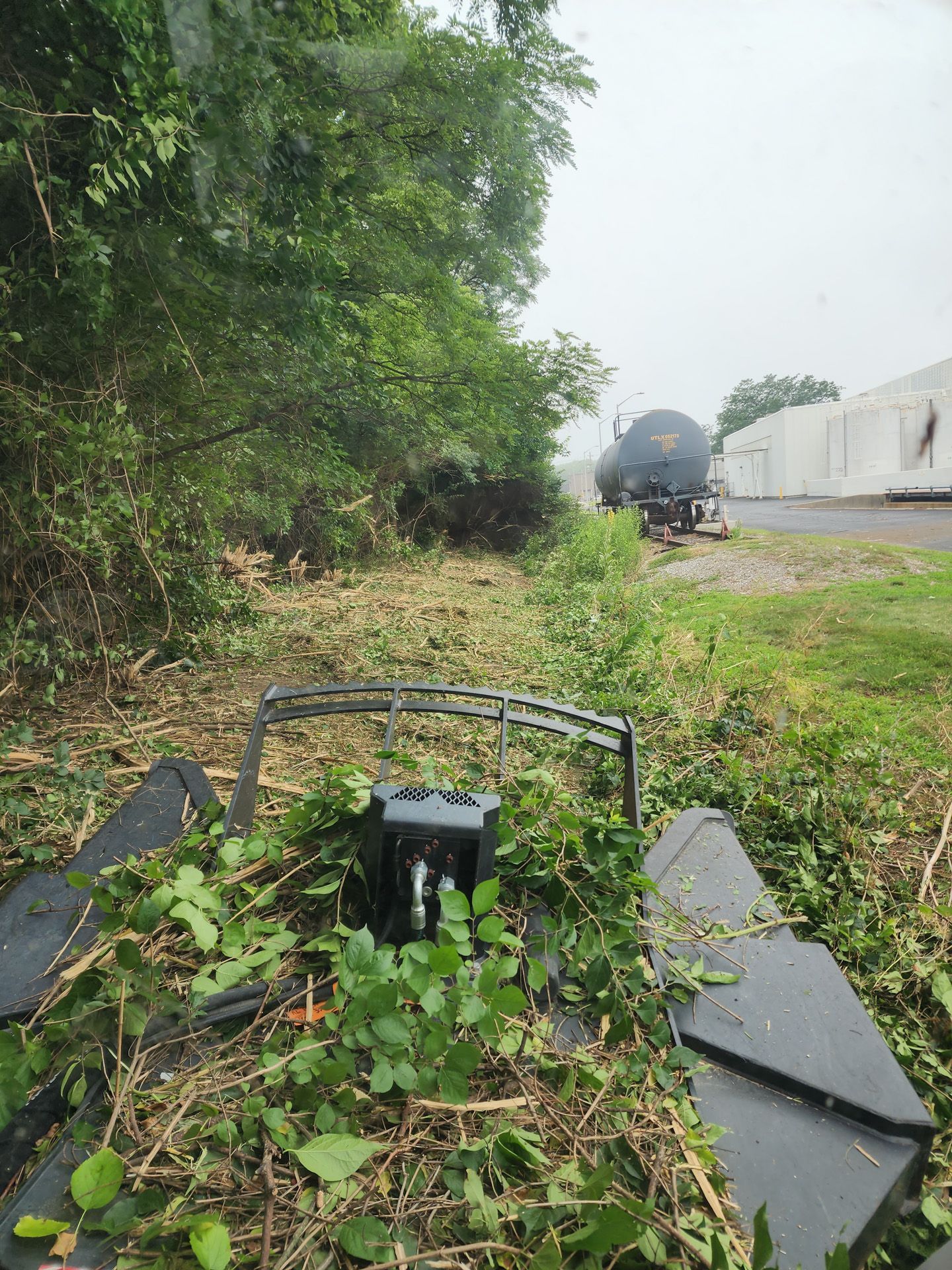 A train car is parked on the side of the road next to a grassy field.