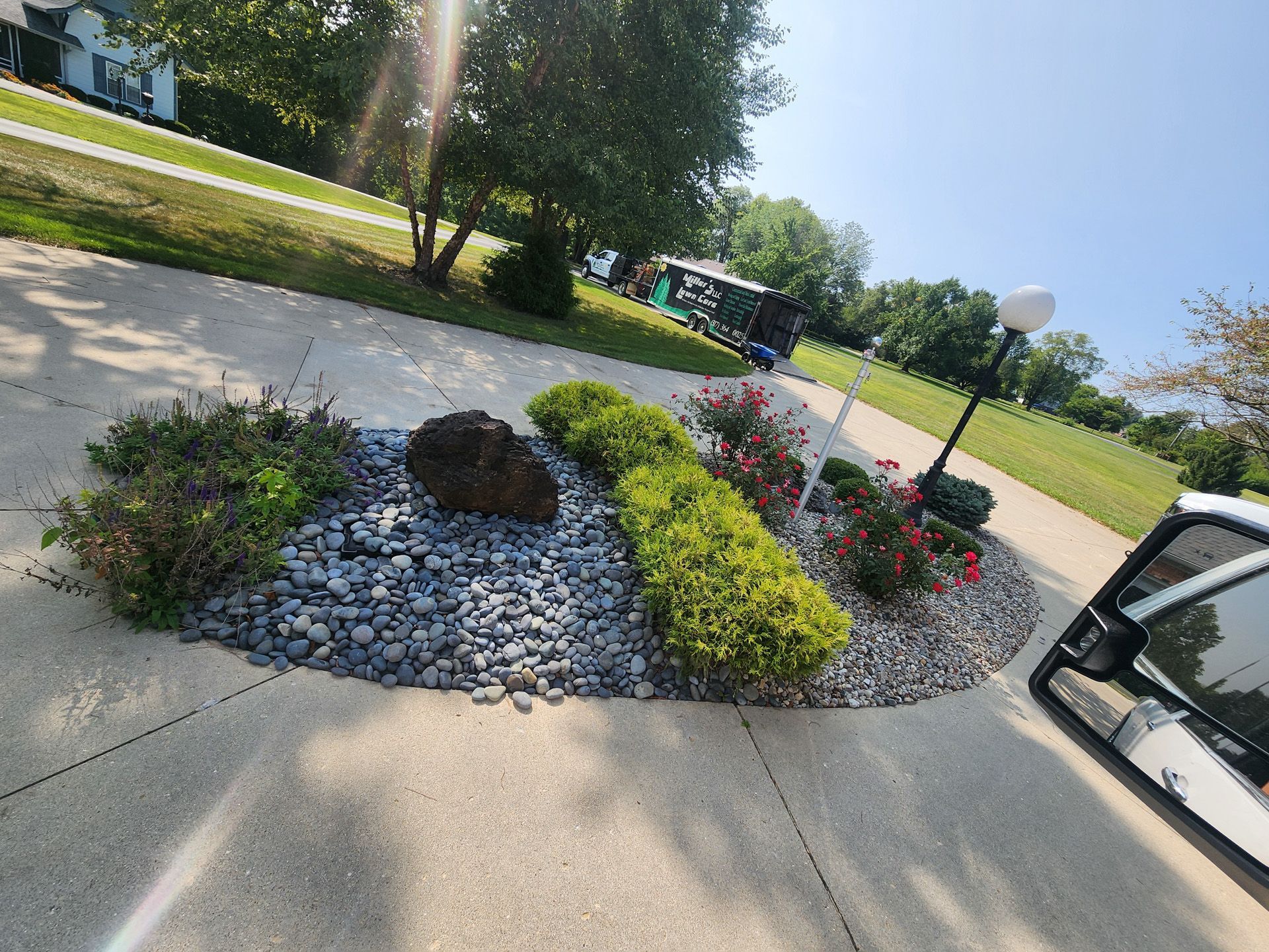 A car is driving down a sidewalk next to a garden.
