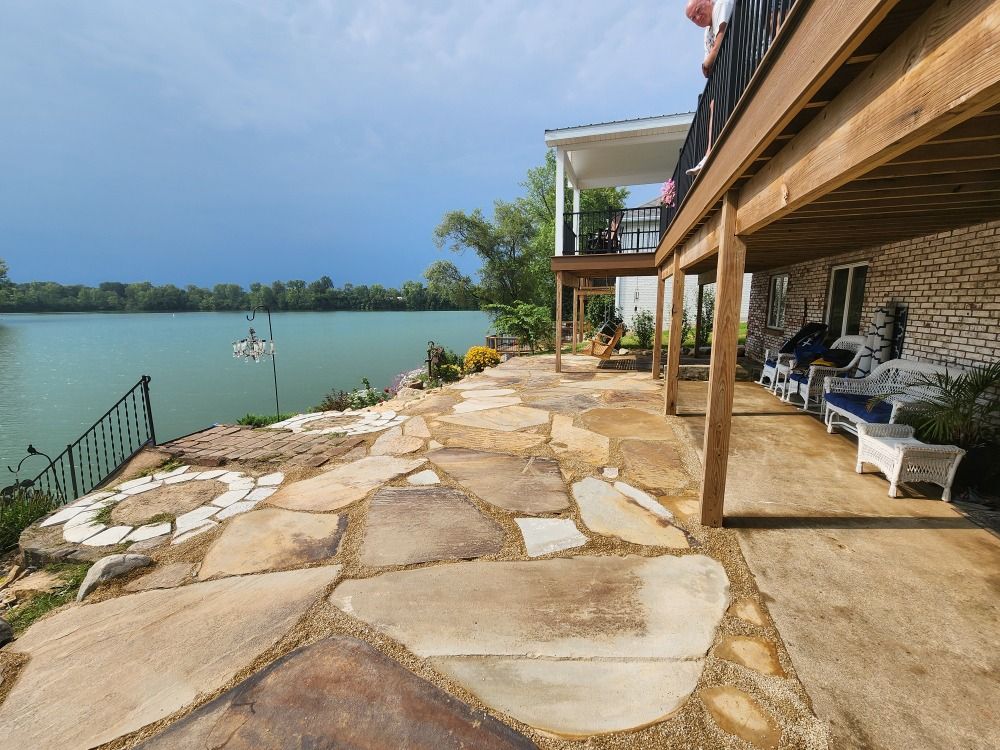 A large house with a large deck overlooking a lake.