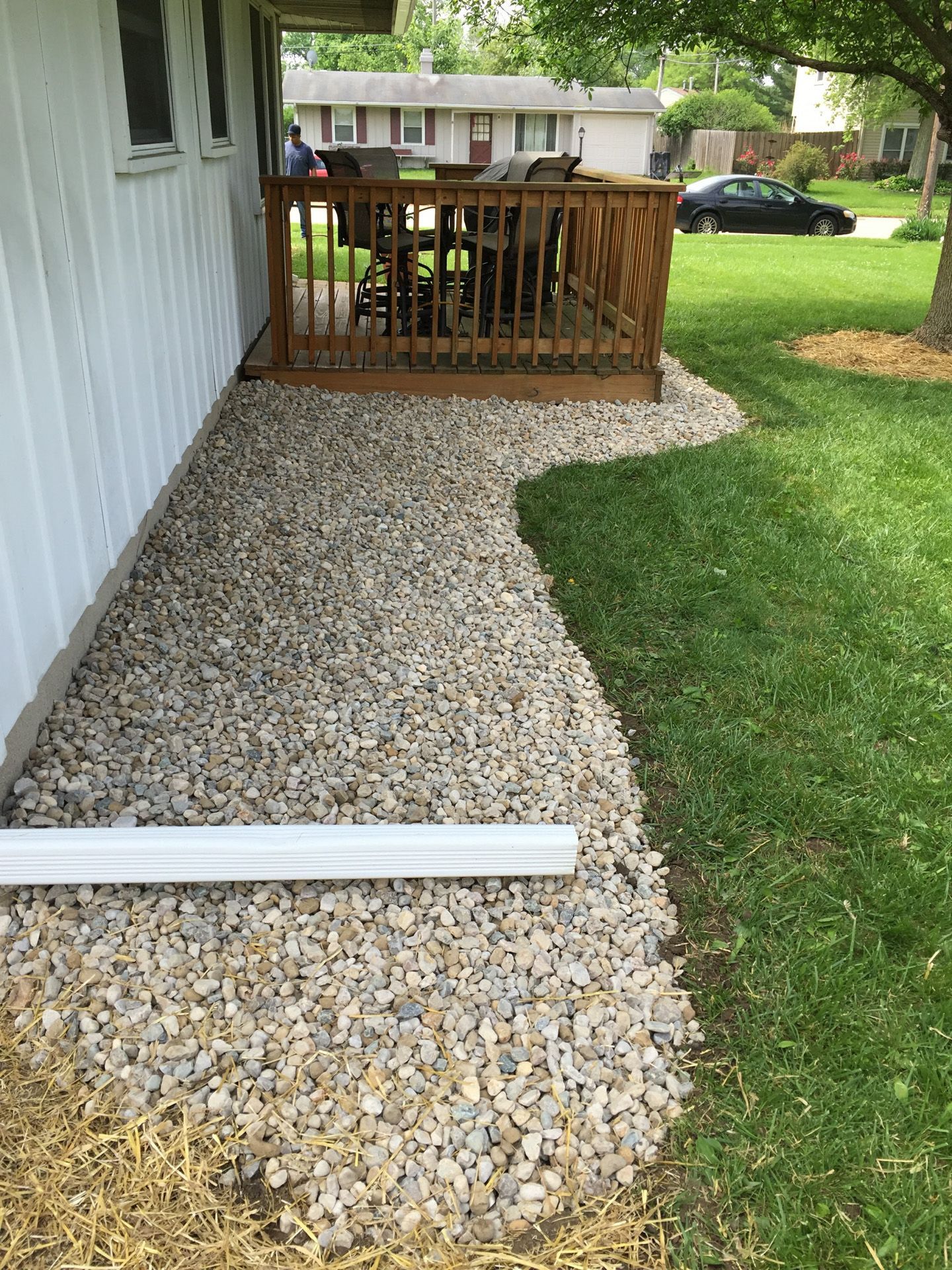 There is a walkway leading to a deck in the backyard of a house.
