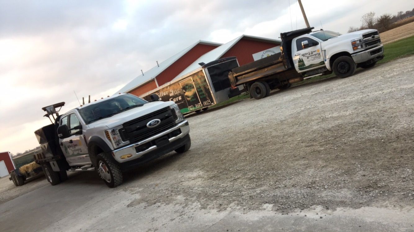 Two trucks are parked next to each other in a gravel lot.