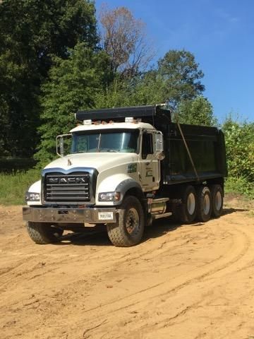 A dump truck is driving down a dirt road.