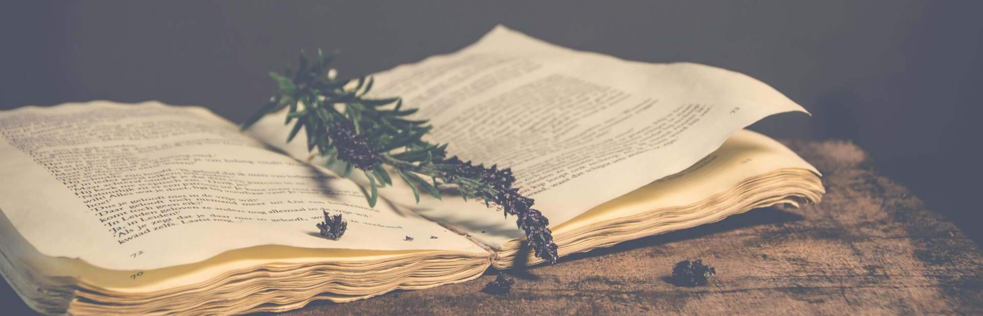 E-reader displaying text next to a stack of physical books on a wooden table. Bookshelf in background.