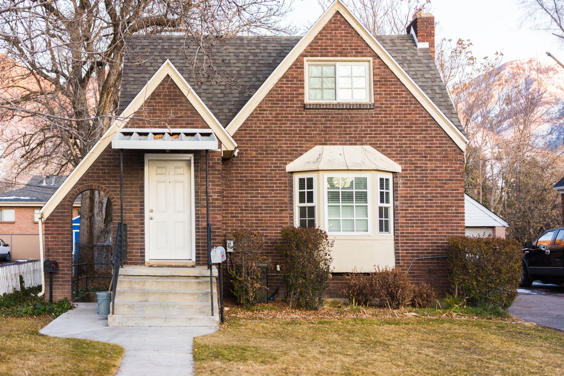 Modern townhomes with white and dark exteriors, large windows, and manicured landscaping under a sunset sky.