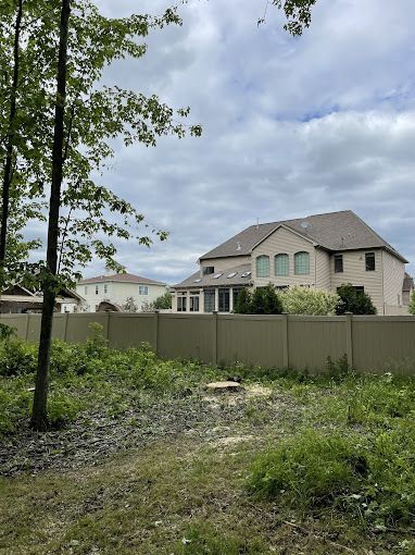 A large house is behind a fence in a residential area.