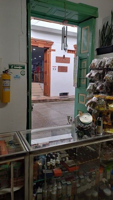 Interior de una pequeña tienda, con vista a través de una puerta verde a una calle estrecha en el exterior.