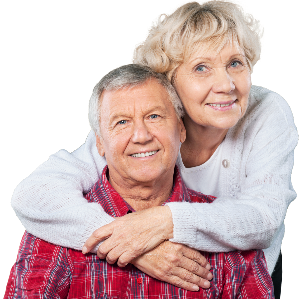 An elderly couple is hugging each other and smiling for the camera.