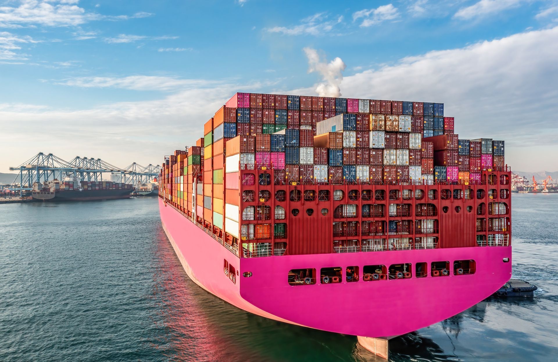 A large pink container ship is floating on top of a body of water.