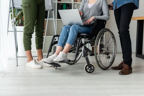 Medical professional assists a patient with a dumbbell exercise in a doctor's office.
