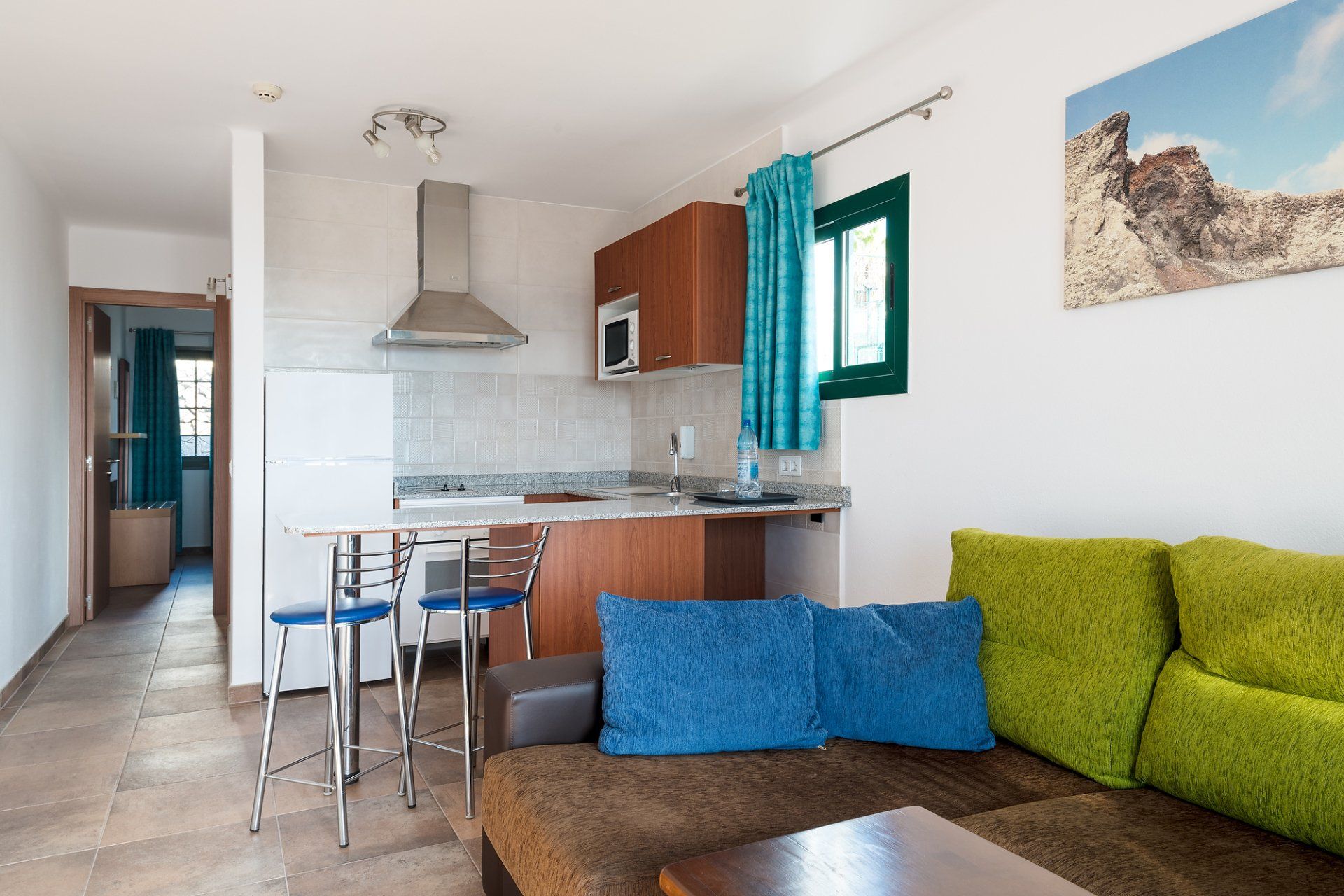 Equipped kitchen with refrigerator, oven, microwave, and bar with stools in Villa Canaima Apartments