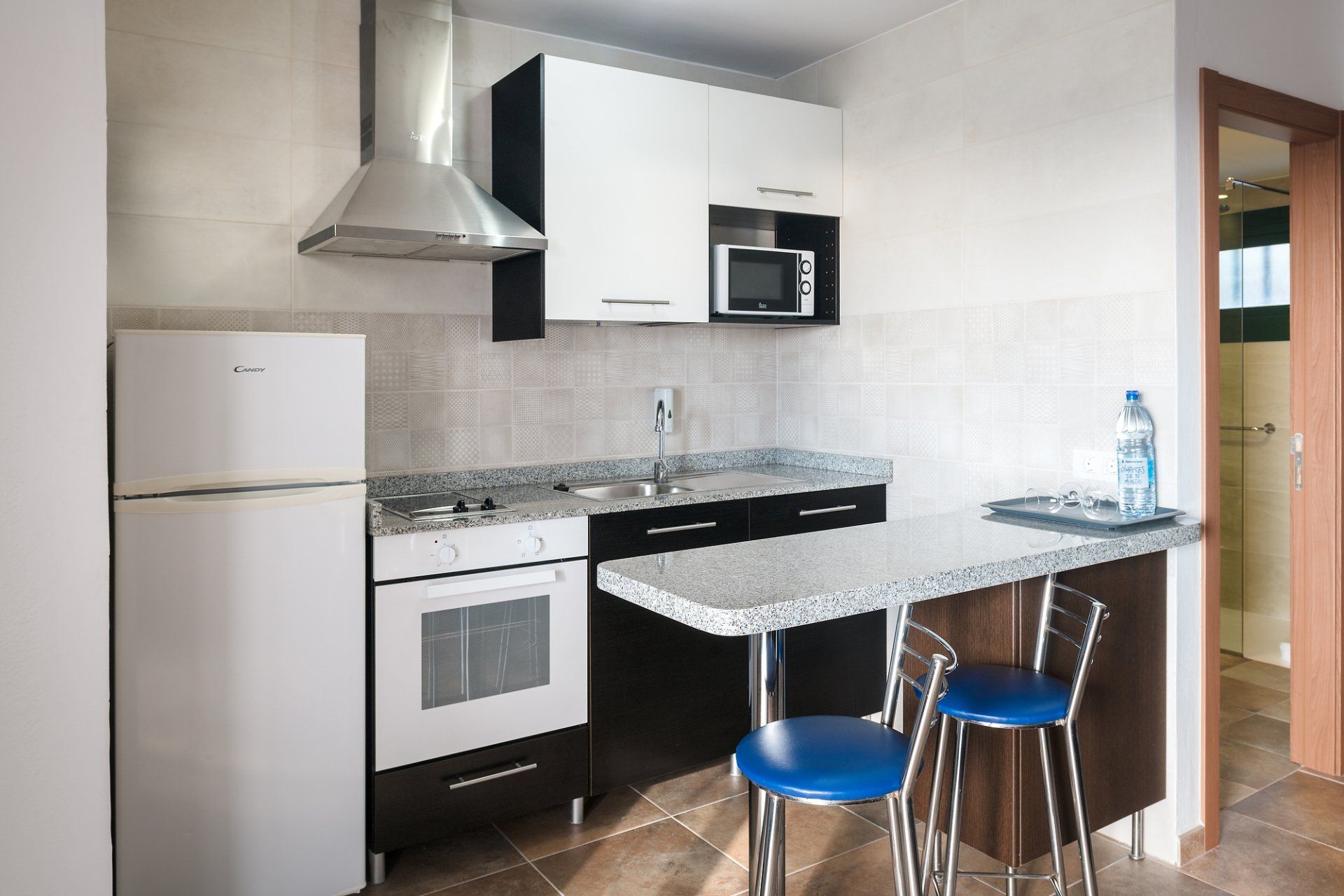 Equipped kitchen with refrigerator, oven, microwave, and bar with stools in Villa Canaima Apartments