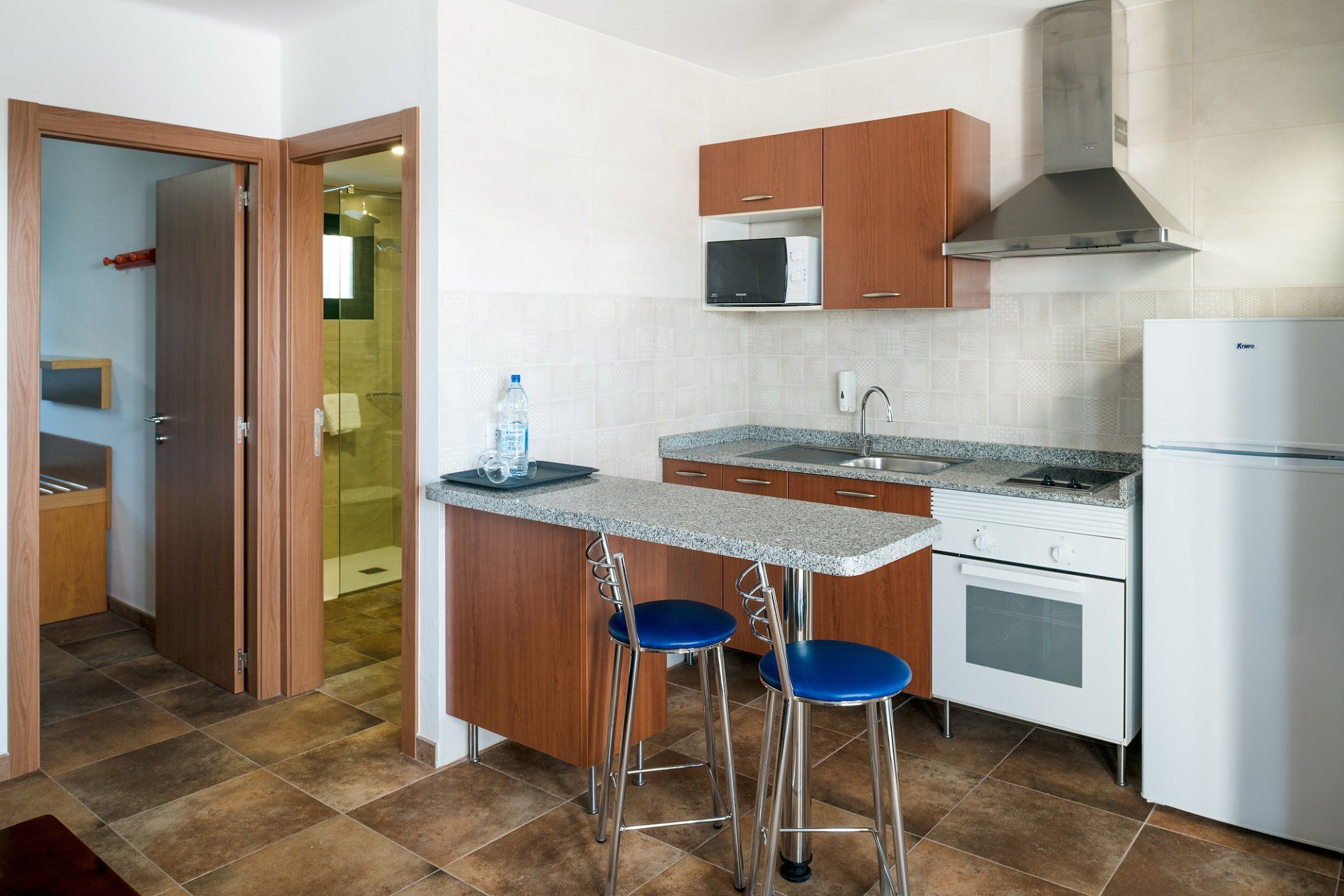 Equipped kitchen with refrigerator, oven, microwave, and bar with stools in Villa Canaima Apartments