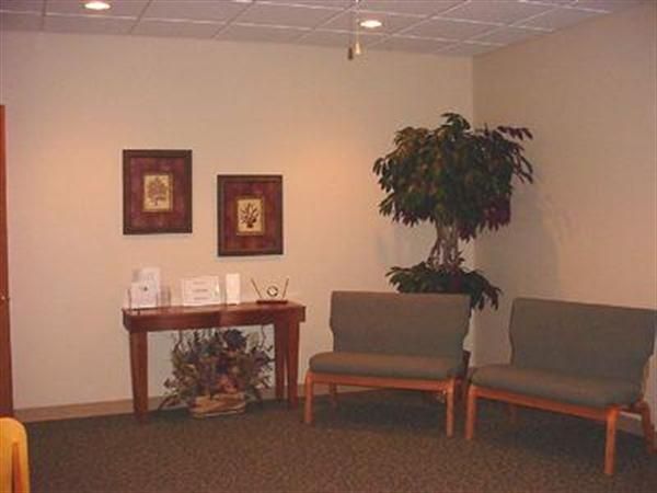 A waiting room with chairs a table and a plant