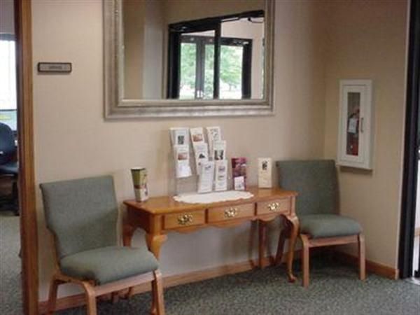 A waiting room with two chairs a desk and a mirror