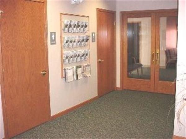 A hallway with wooden doors and a green carpet