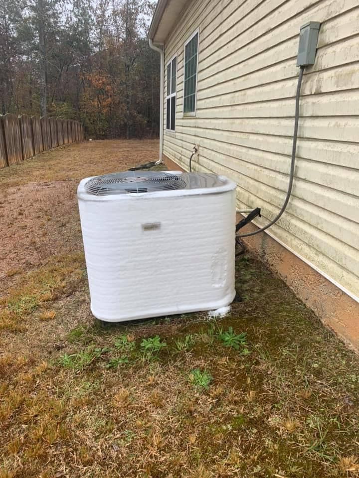 A white air conditioner is sitting on the side of a house.