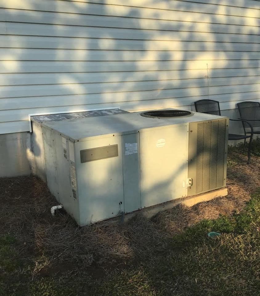 A large box is sitting in the dirt in front of a house.