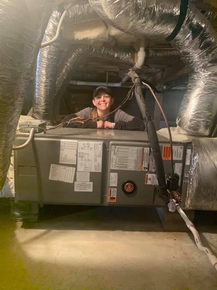 A young boy is standing in a basement next to an air conditioner.