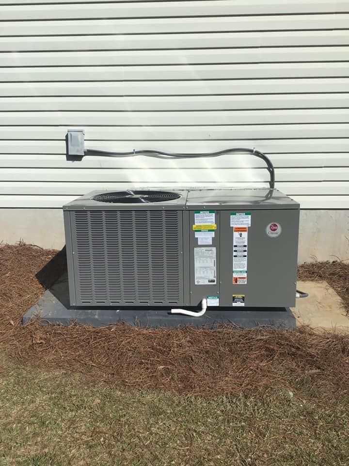 An air conditioner is sitting on top of a concrete slab in front of a house.