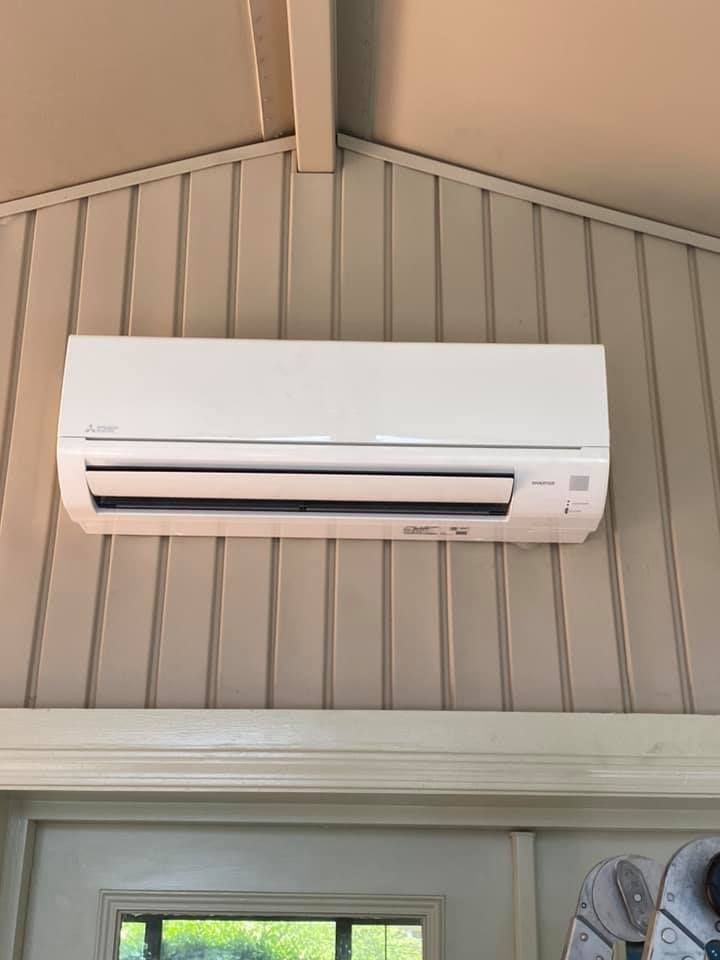 A white air conditioner is hanging from the ceiling in a room.